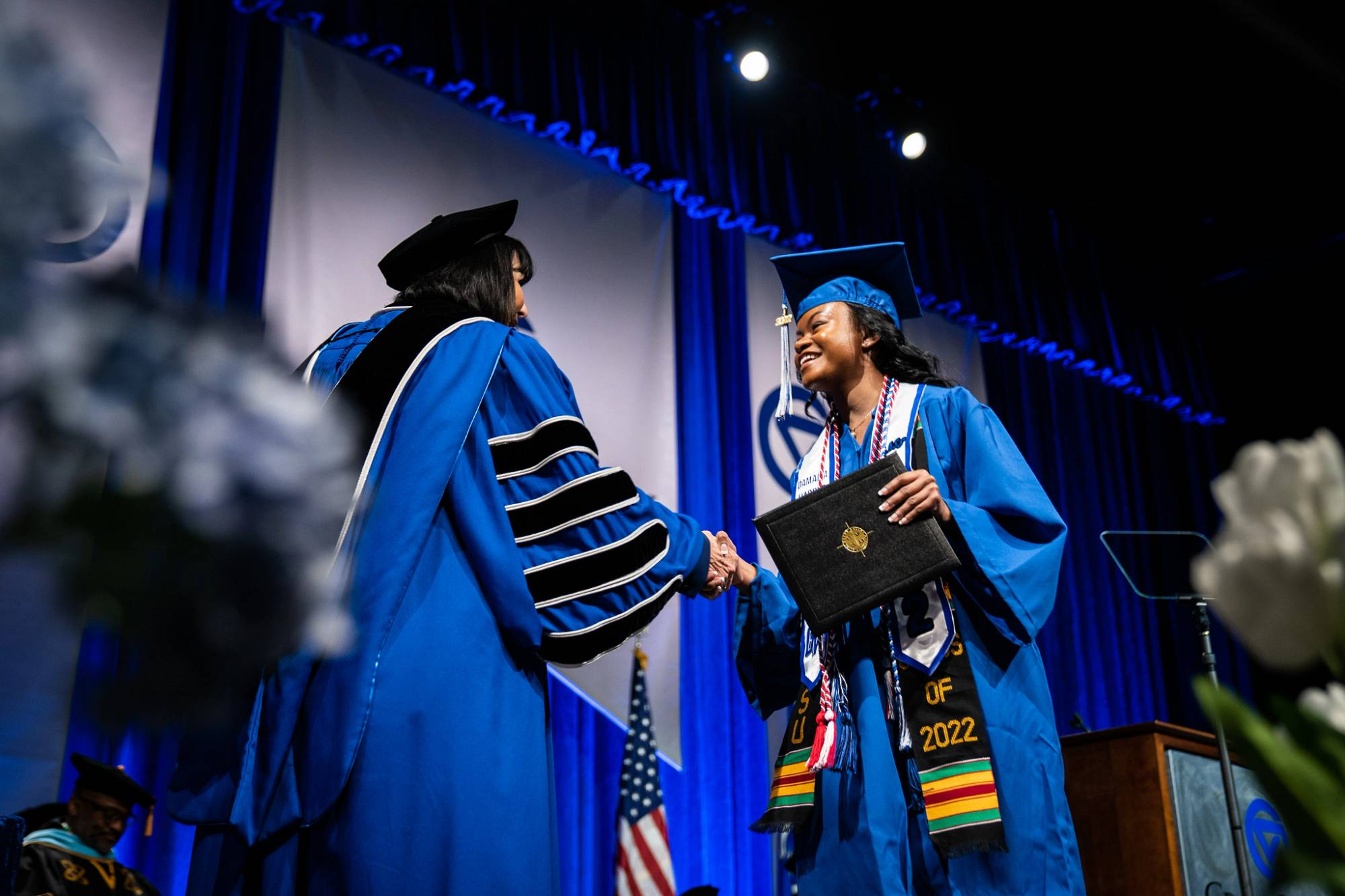 A graduate smiles while shaking President Mantella's hand during Commencement